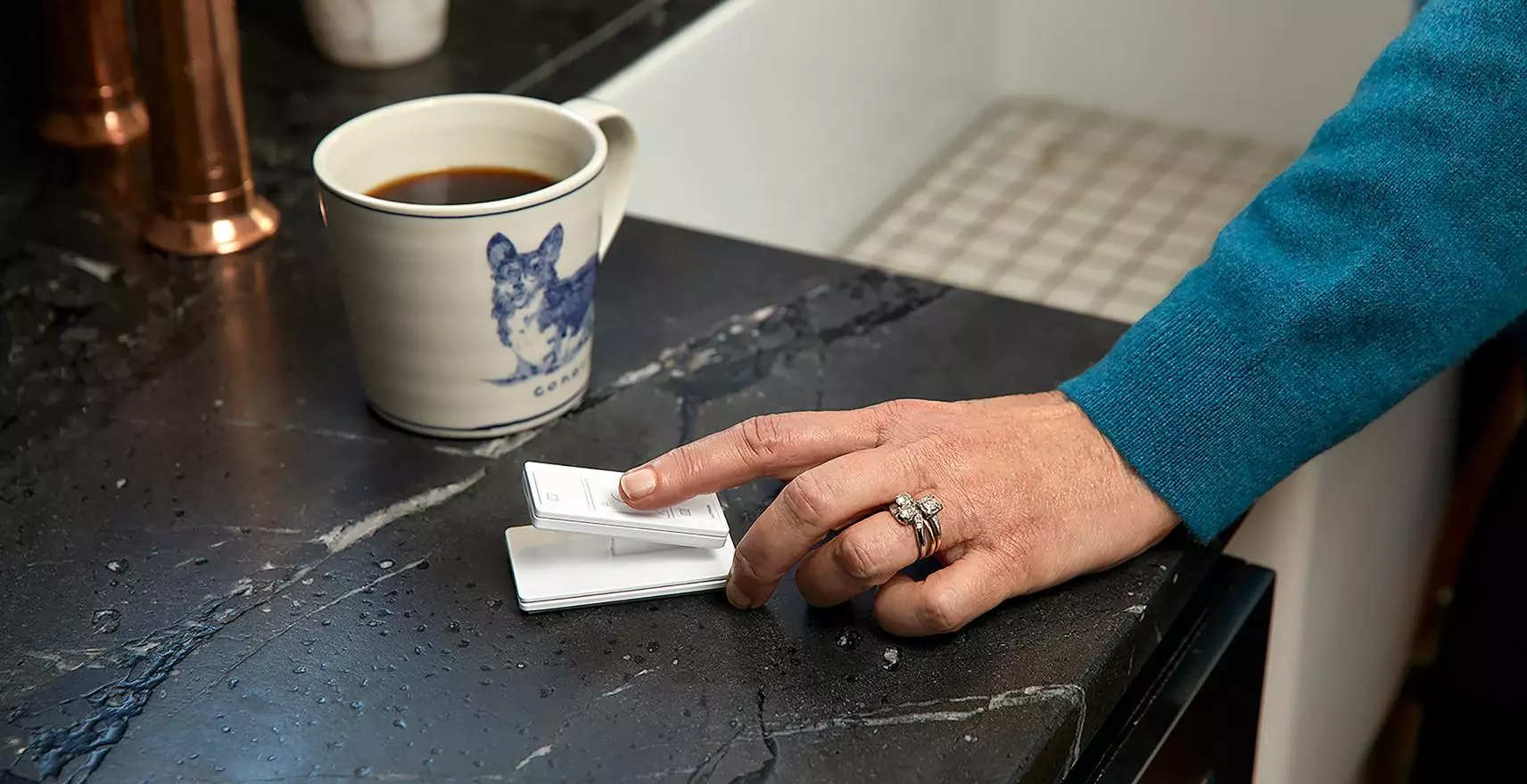 Hand using Lutron Pico remote with coffee cup showing lifestyle integration